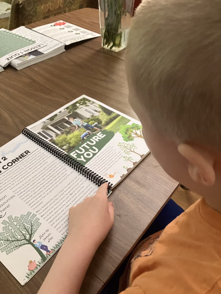 Personal finance is an important life skill to teach your homeschoolers. Beyond Personal Finance offers kids real practice in this skill. A child reads about future you inside of Before Personal Finance. 