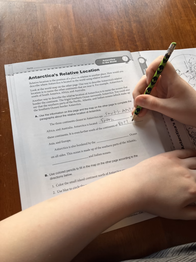 A child fills out a page about Antarctica's Relative Location in the 7 Continents Antarctica book. 