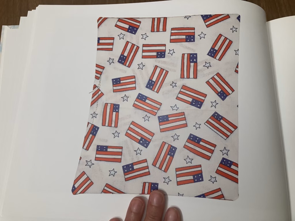 A page of the Arkive book in which a photograph of sewn napkin appears. The napkin has a background with American flags and stars.